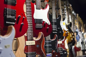 Store enrouleur Magasin de musique De nombreuses guitares électriques accrochées au mur de la boutique.