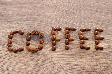 word coffee written with coffee beans on wooden background