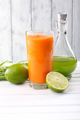 Glass of fresh carrot juice, decanter of lime juice, lime, tuft