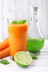 Glass of fresh carrot juice, decanter of lime juice, lime,