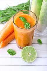 Glass of fresh carrot juice, spring onion, lime, tuft of grass