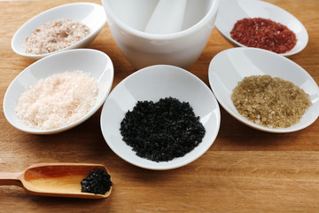 Variety of different sea salt in bowls on wooden table, close