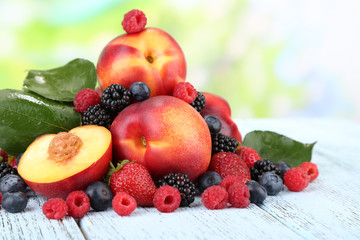 Peaches with berries on table on natural background