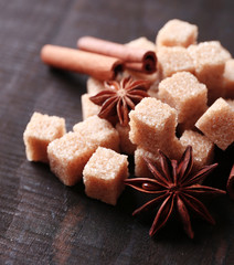 Brown sugar cubes and reed sugar, spices on wooden background