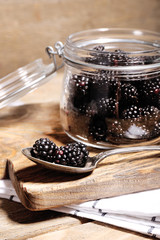 Sweet blackberries in glass jar on color wooden background © Africa Studio