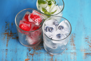 Ice cubes with mint leaves, raspberry and blueberry in glasses,