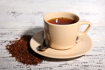 Cup of tasty rooibos tea, on old white wooden table