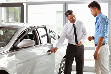 Car Showroom. Vehicle Dealer Showing Young Man New Car