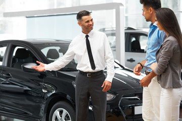 Сar Salesman Invites Customers at Showroom.