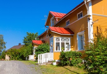 Fototapeta na wymiar Wooden yellow house with red roof in Scandinavian style