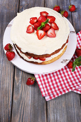 Delicious biscuit cake with strawberries on table close-up