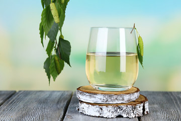 Glass of fresh birch sap on a wooden table on nature background - obrazy, fototapety, plakaty