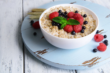 Tasty oatmeal with berries on table close-up