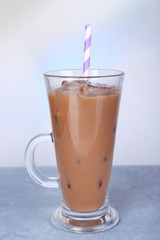 Glass of iced milk coffee on light background