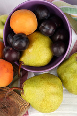 Ripe fruits in bowl on table close up