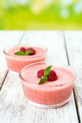 Delicious berry mousse in bowls on table on bright background