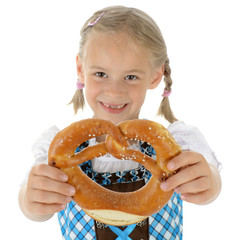 Kind in Dirndl zum Oktoberfest hält Brezel