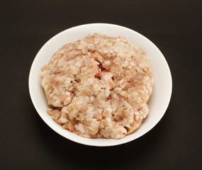 Minced pork meat in the white bow on the black background