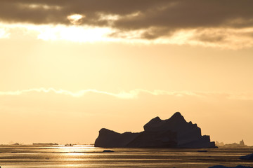 Iceberg in Antarctic waters in the rays of the setting sun on a