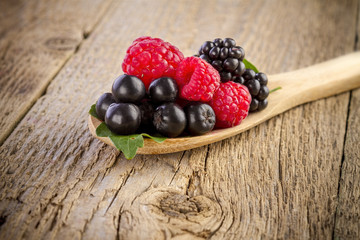 forest berries in wooden spoon on wooden table
