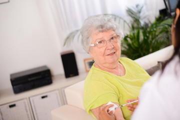 cheerful elderly woman receiving injection from a young nurse