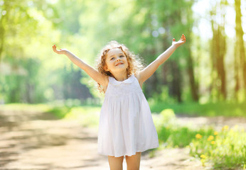 Charming little girl enjoying summer sunny day, raises his hands © rohappy