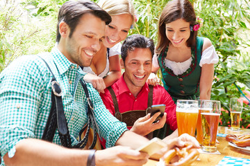 Freunde im Biergarten schauen auf Smartphones