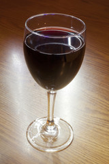 A glass of Red Wine on a wooden table.