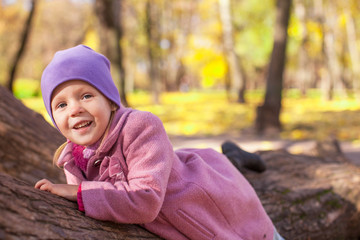 Little cute girl in autumn park on sunny day outdoor