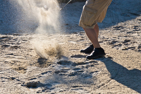Golf player hitting the ball from the sand bunker