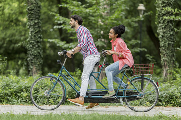 Young couple riding on the tandem bicycle