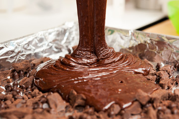 pouring mixture of chocolate eggs and flour preparing for bake b