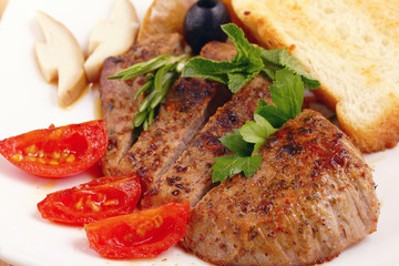 serving of meat with vegetables on a plate of white background