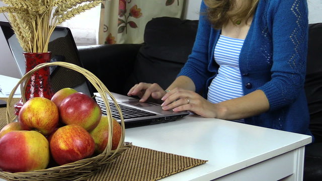 close up of pregnant woman with blue sweater stamp computer keys