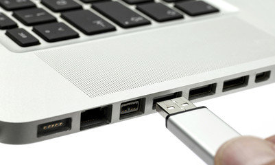 Hand steckt USB-Stecker in laptop