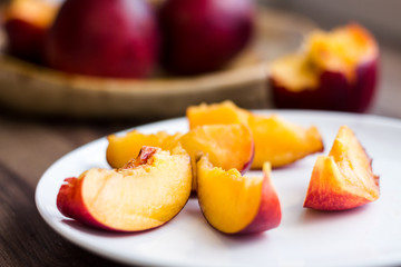 Fototapeta na wymiar Juicy slices of peach on a white round plate, horizontally