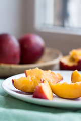 peaches, juicy slices on white round plate, green napkin