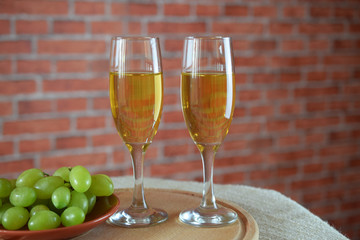 Grapes and two glasses of the white wine on a red brick