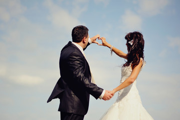 Fototapeta na wymiar groom and bride shows symbol of heart