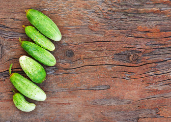 Juicy ripe green cucumbers on old wooden background.