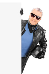 Mature biker posing behind a blank billboard