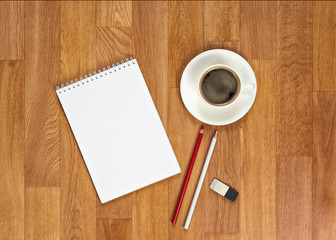 Blank notepad with office supplies and cup of coffee on wooden t