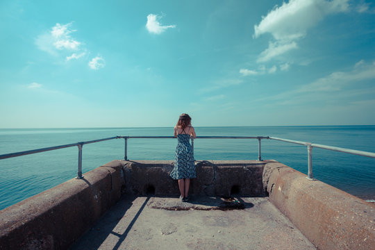 Young woman standing on a pier by the ocean