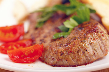 serving of meat with vegetables on a plate of white background