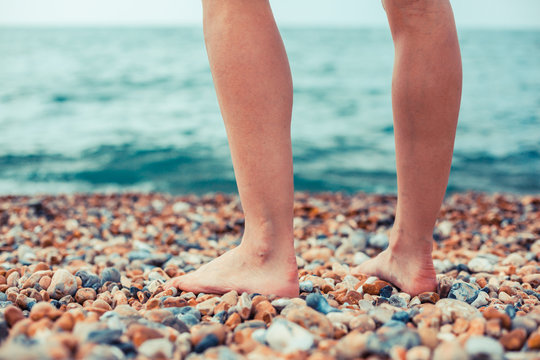 The feet of a young woman standing on the beach