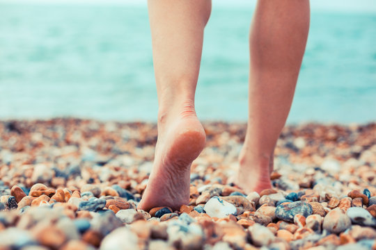 The feet of a young woman standing on the beach