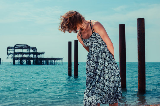 Young woman standing by the ocean with old pier