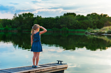 Fototapeta na wymiar Outdoor portrait of a cute little girl, standing on a pier