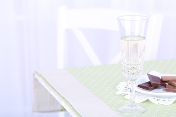 Glass of champagne and chocolate on table, close up