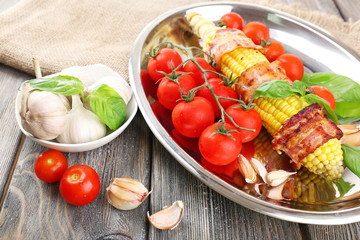 Grilled bacon wrapped corn on table, close-up